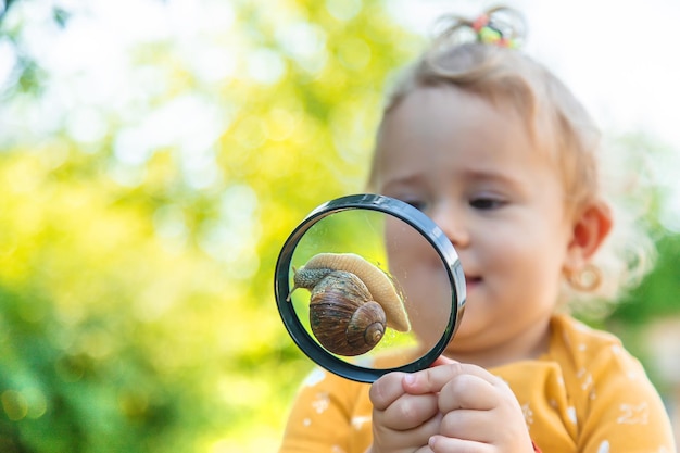 Foto het kind kijkt naar de slak selectieve focus