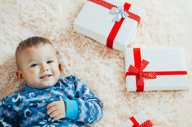Foto het kind ligt op de pluizige wollige deken, naast hem een heleboel cadeaus, het kind is erg blij