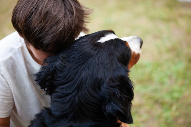 Het kind omhelst zijn hond terwijl hij zijn hoofd laat rusten als een teken van genegenheid en troost.