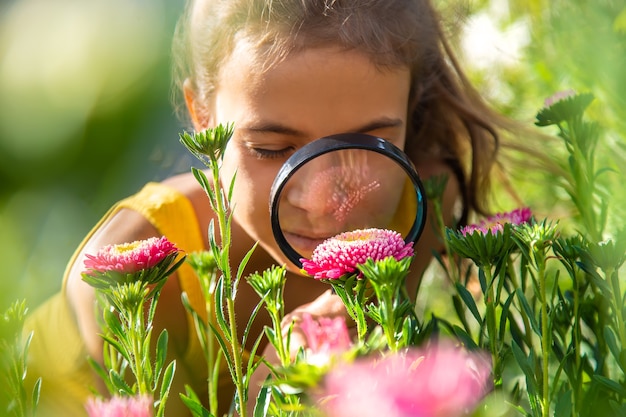 Het kind onderzoekt de planten met een vergrootglas. Selectieve aandacht.