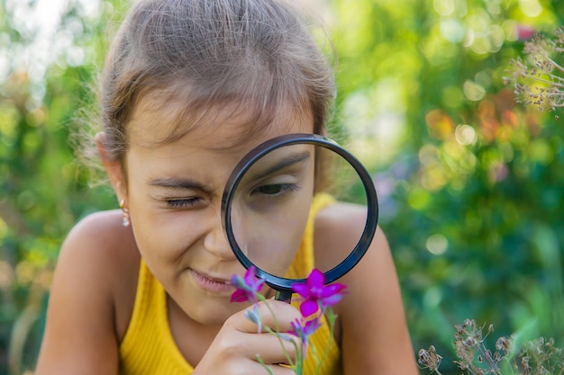 Het kind onderzoekt de planten met een vergrootglas. Selectieve aandacht.