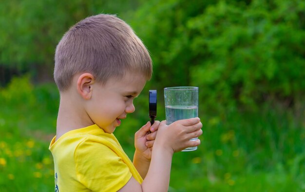 Het kind onderzoekt het water met een vergrootglas in een glas Selectieve focus