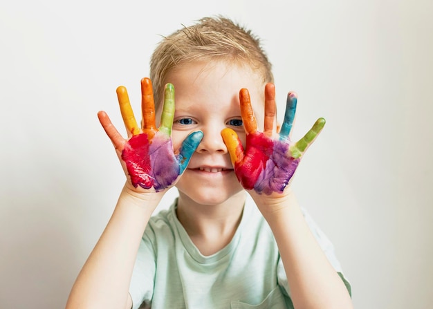 Het kind schildert handpalmen en handen van een kind in veelkleurige aquarel aquarel gouache penselen gekleurd en waskrijtjes stickers set voor het tekenen van creativiteit en hobby's