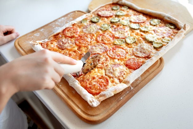 Het kind snijdt pizza met een rolsnijder dicht omhoog