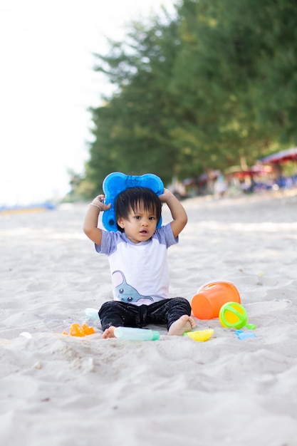 Het kind speelt alleen op een wit strand met een emmer en een zandschop van dichtbij