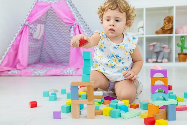 Het kind speelt in de kinderkamer met een houten constructeur Selectieve focus