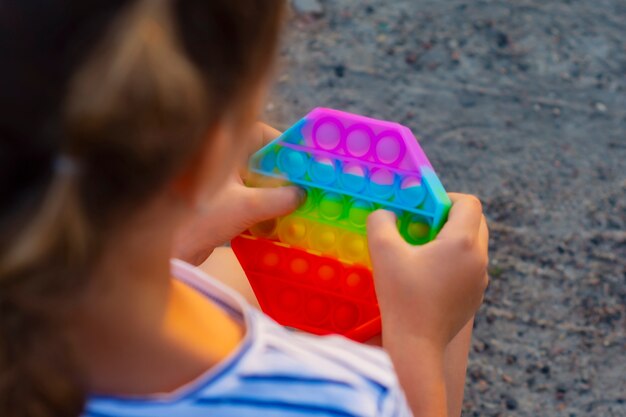 Het kind speelt met een kleurrijk regenboogspel poppit. Siliconen fidget close-up.