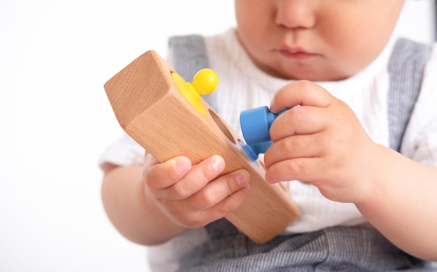 Het kind speelt met kleurrijke speelgoedblokken Eco houten speelgoed Klein slim kind dat natuurlijke speelgoedspellen speelt voor de vroege ontwikkeling Speelgoed in kinderhanden close-up