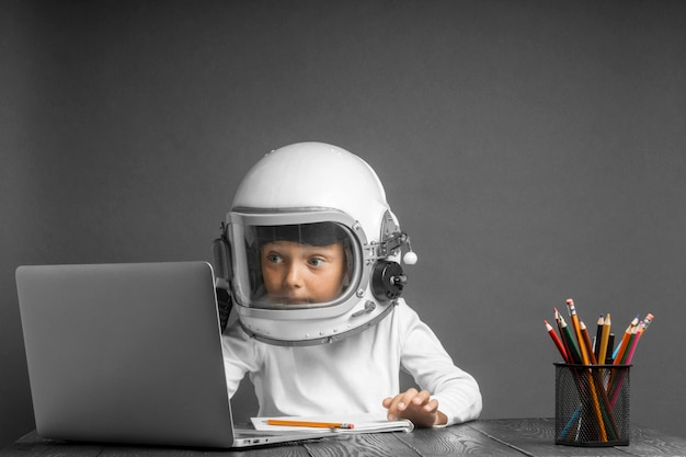 Het kind studeert op afstand op school, met een astronautenhelm op. terug naar school