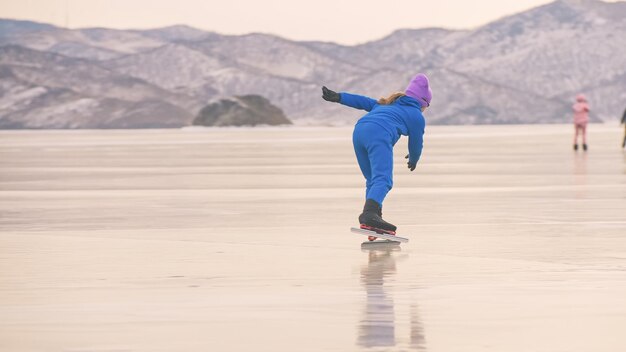 Het kind traint op professionele ijsschaatsen. Het meisje schaatst in de winter in sportkleding, sportbril, pak. Buiten slowmotion.