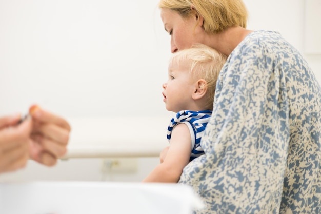 Het kind wordt door een kinderarts in aanwezigheid van zijn moeder ingeënt tegen preventieve vaccinatie tegen dippie.