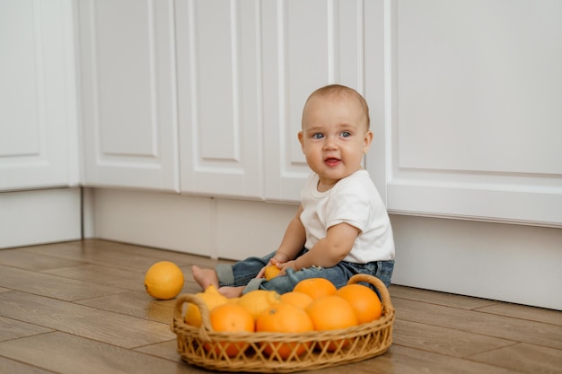 het kind zit op de keukenvloer met een mand met citrusvruchten
