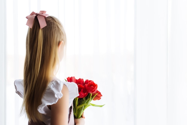 Het kleine boeket van de meisjesholding van rode tulpenbloemen. Concept voor wenskaart