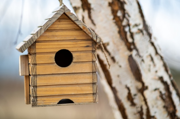 Het kleine houten vogelhuis hangen op een boomtak in openlucht.