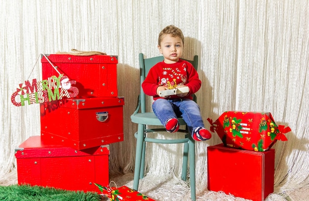 Het kleine kind speelt met kerstversieringen in de studio. Het kleine kind met de kerstbal.