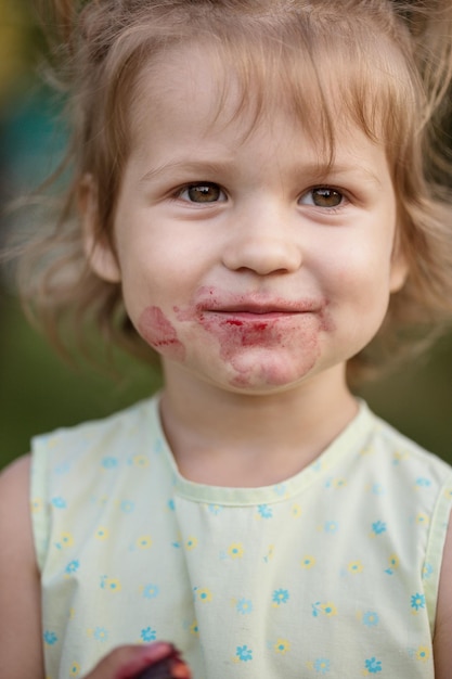 Foto het kleine meisje eet kers in de tuin. zomer