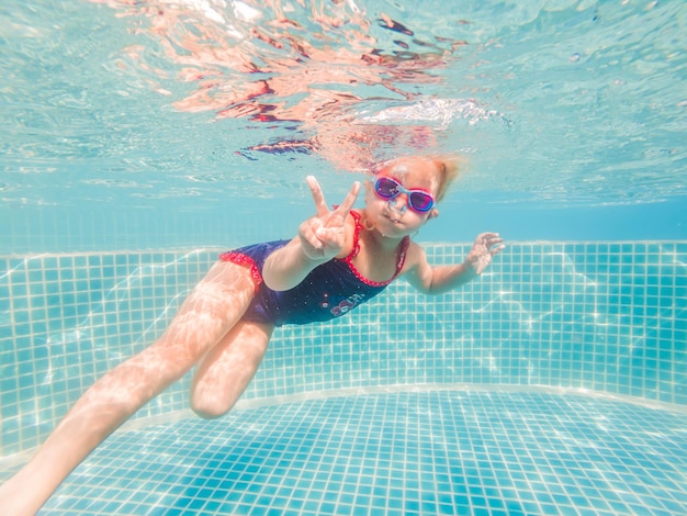 Het kleine meisje in het waterpark dat onder water zwemt en glimlacht