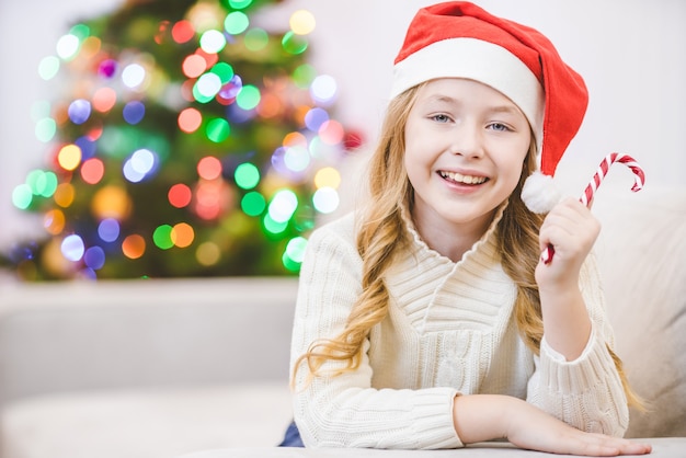 Het kleine meisje met een snoepje lag bij de kerstboom