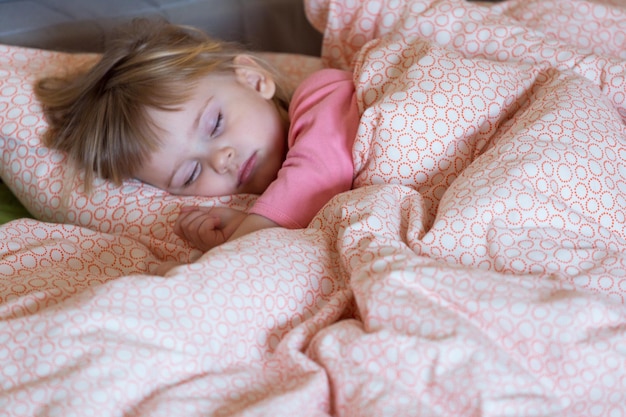 Het kleine meisje slaapt in het bed van de ouders Slapen in een dag Selectieve focus