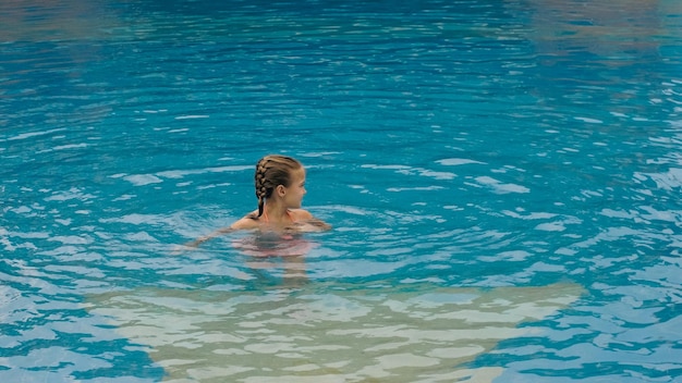 Het kleine schattige meisje heeft plezier in het zwembad Het kind geniet van de zomervakantie in een zwembad