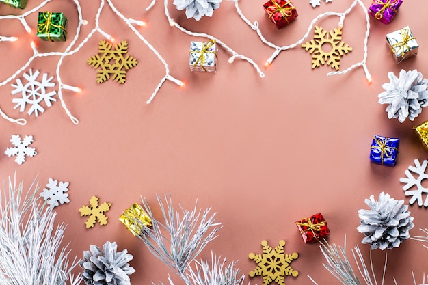 Het kleurrijke Kerstmiskader met sneeuwvlokken, stelt en Kerstmislichten op een warme bruine achtergrond voor