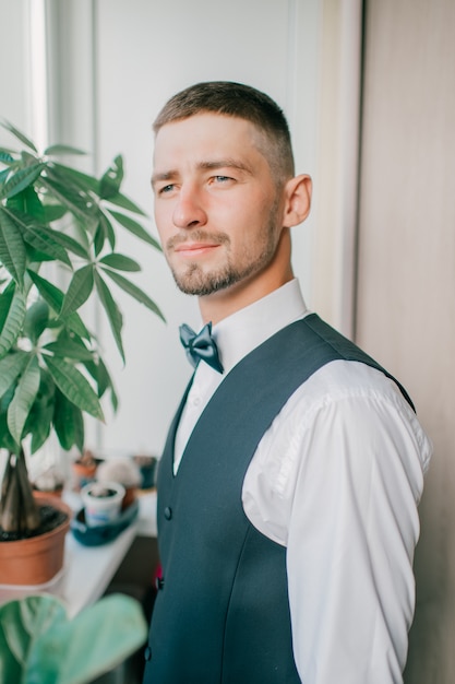 Foto het knappe elegante bruidegom binnen stellen.