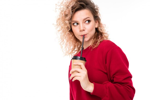 Het knappe kaukasische wijfje met krullend eerlijk haar drinkt coffe geïsoleerd op witte achtergrond