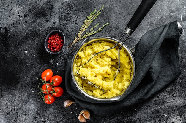 Het koken van aardappelpuree in een pot. zwarte achtergrond. bovenaanzicht