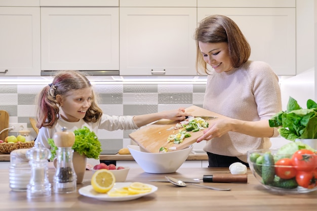 Het koken van de moeder en van de dochter samen in keuken plantaardige salade