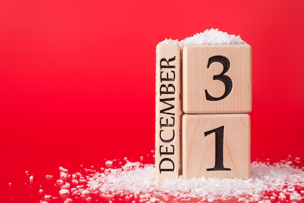Het laatste dag van het jaarconcept. Close-up foto van houten kubussen kalender met de laatste datum van het jaar geïsoleerd op rode achtergrond met sneeuw