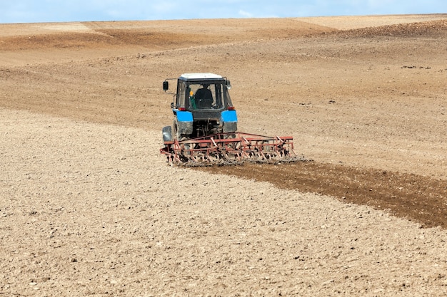 Het landbouwveld, dat in een tractor ploegde die de grond voorbereidde voor het planten. Voorjaar