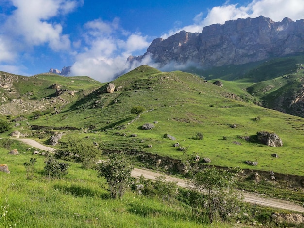 Het landschap van de groene Aktoprak-pas in de Kaukasus, de weg en de bergen onder grijze wolken Rusland