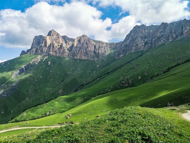 Het landschap van de groene Aktoprak-pas in de Kaukasus, de weg en de bergen onder grijze wolken