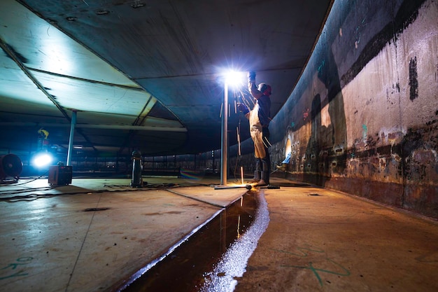 Het lassen van metaal van de mannelijke werknemer maakt deel uit van de constructie van de machineplaat, de tankbalk, flitsvonk in besloten ruimtes