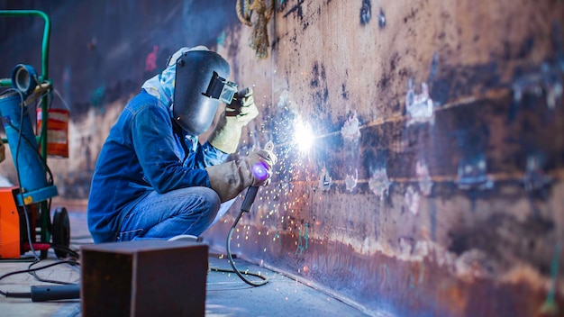 Het lassen van metaal voor mannelijke werknemers maakt deel uit van de constructie van de tankwand van de machinetank, aardolie- en gasopslagtank in besloten ruimtes.