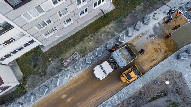 Het leggen van bestratingsplaten op het voorbereide betonnen oppervlak Reparatie van het voetpad in de stad stedelijk gemeentelijk werk