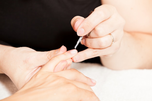 Het leggen van nagellak op de handen van een vrouw