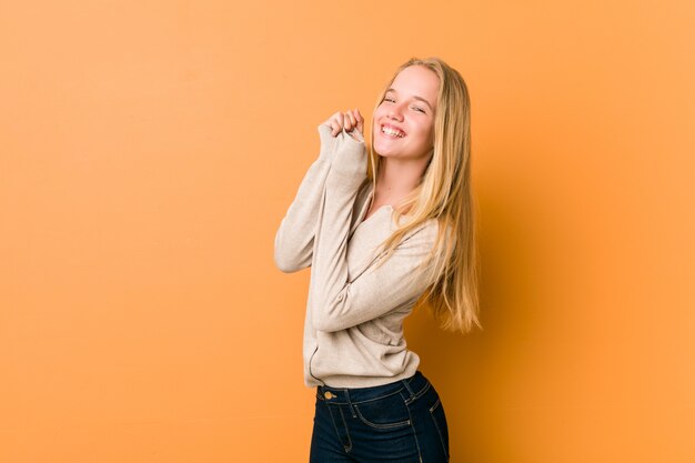 Het leuke Kaukasische tiener stellen die zich tegen een oranje achtergrond bevinden