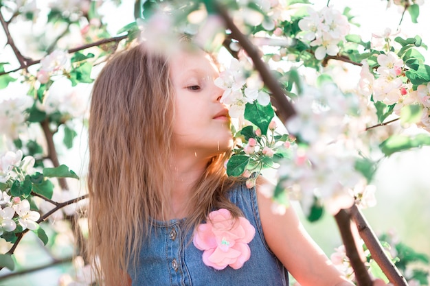 Het leuke meisje in de bloeiende tuin van de appelboom geniet van de warme dag