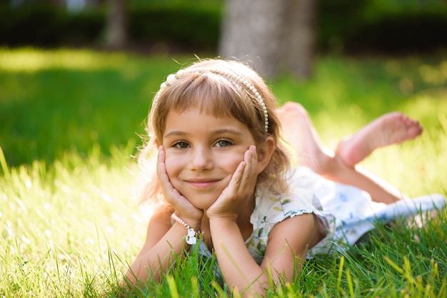 Het leuke meisje ligt op gras in de zomerpark