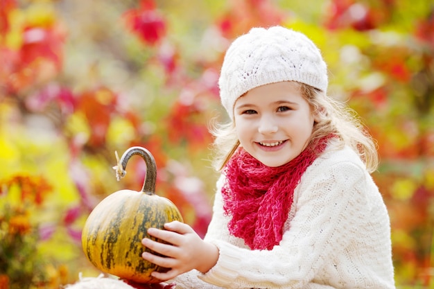 Het leuke meisje spelen met pompoenen in de herfstpark. Herfstactiviteiten voor kinderen