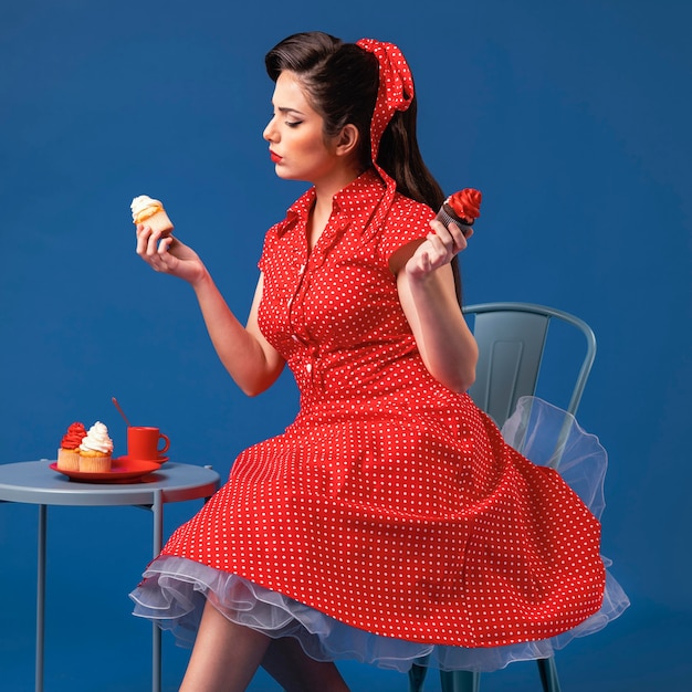 Foto het leuke pinupmeisje stellen in een blauwe studio