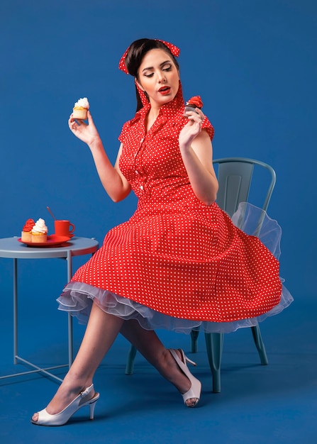 Foto het leuke pinupmeisje stellen in een blauwe studio