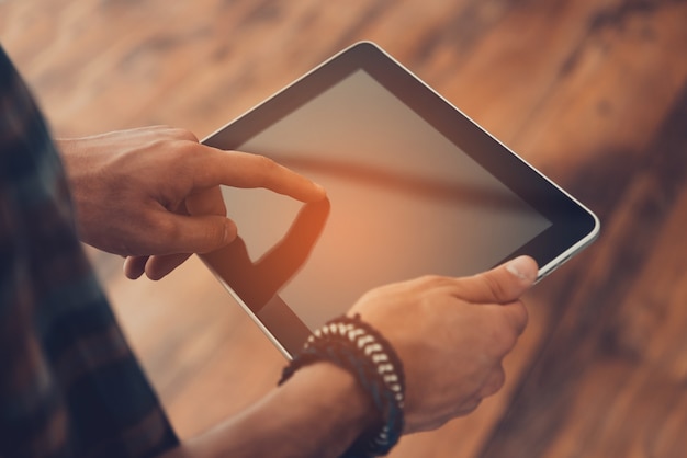 Het leven gemakkelijker maken met slimme technologieën. Close-up van een man die een digitale tablet gebruikt terwijl hij op de houten vloer staat