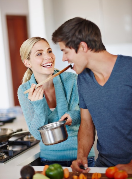 Foto het leven is heerlijk foto van een mooie jonge vrouw die haar man laat proeven van haar kookkunsten