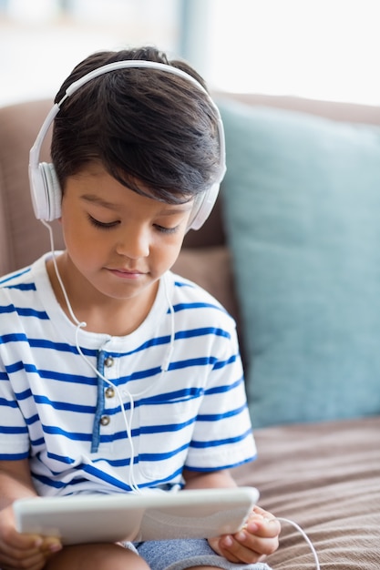 Het luisteren van de jongen muziek op digitale tablet in woonkamer