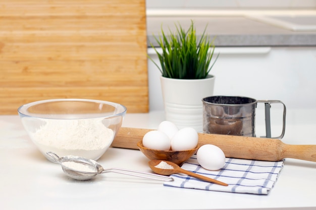 Het maken van deeg voor brood of zelfgemaakt gebak. ingrediënten op tafel. tegen de achtergrond van een lichte, moderne keuken