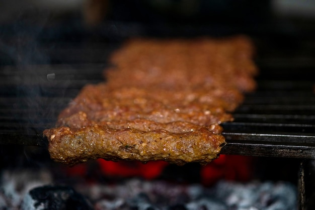 Het maken van pittige seekh-kebabs worden gegrild op brandende houtskool in de barbecue tijdens een etentje 's avonds