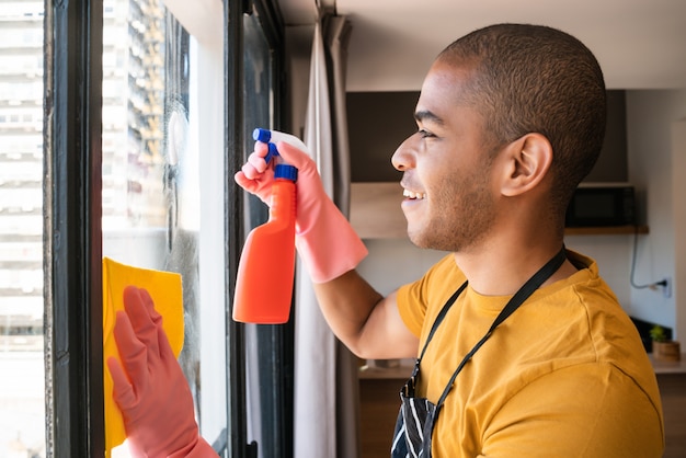 Het mannelijke venster van het huishoudster schoonmakende glas thuis.