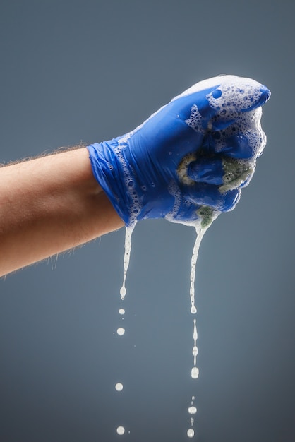 Het mannetje dient blauwe handschoen met druipend schuim in